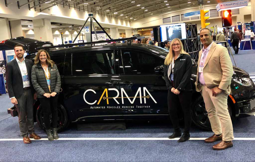Four people standing in front of CARMA branded vehicle